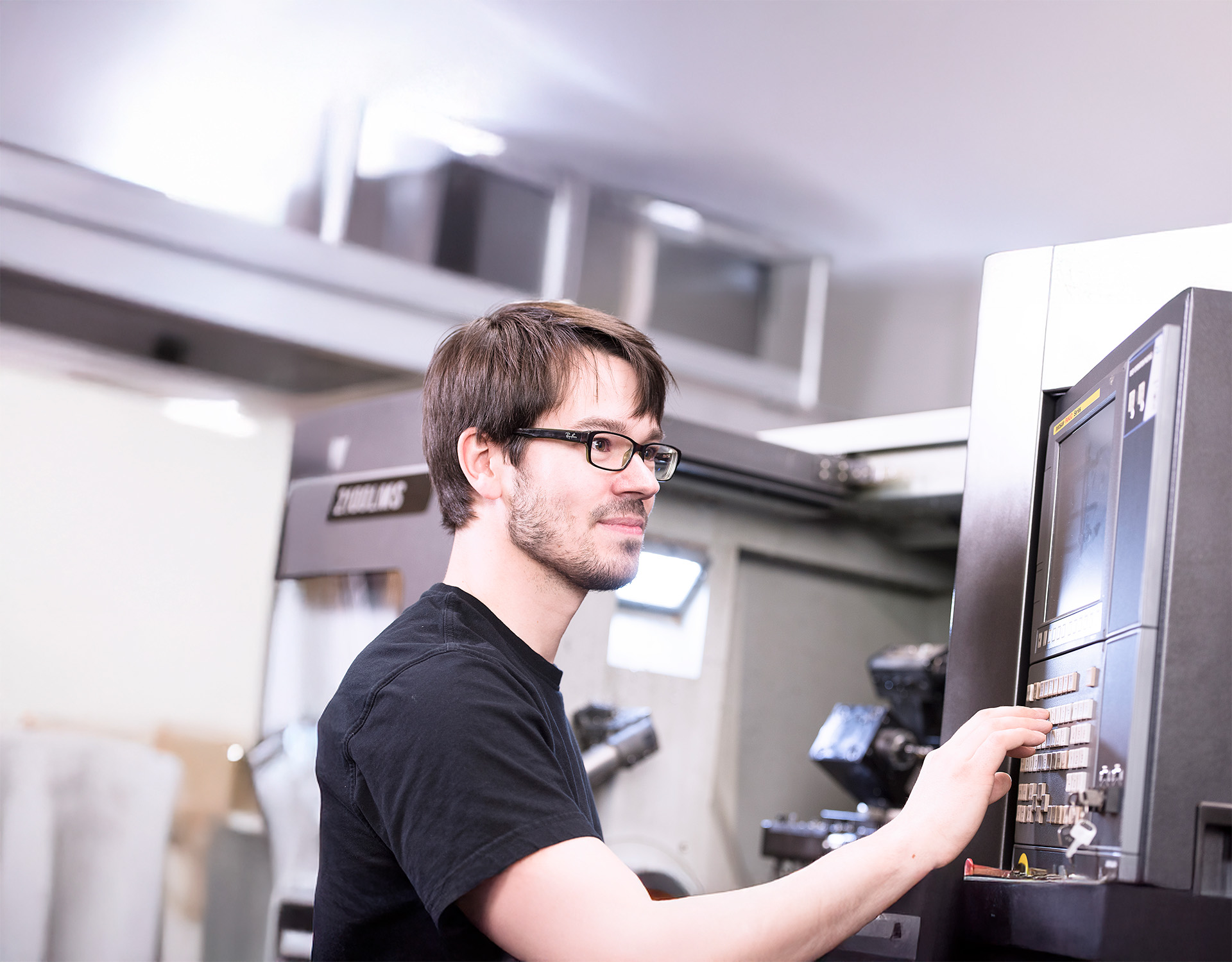 Mitarbeiter bedient eine CNC-Maschine in der industriellen Fertigung von Injektoren und Zubehör für die Partikelschaumindustrie bei Peter Kröner GmbH.