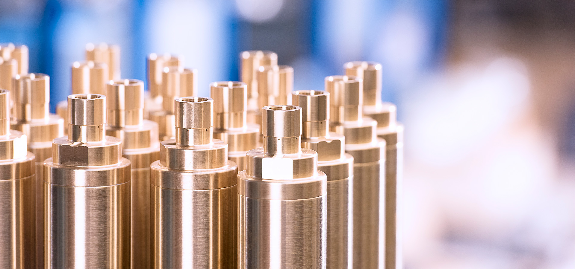 Glanzende metallische Zylinderkomponenten, typische Produkte von Die Peter Kröner GmbH für die Partikelschaumindustrie, darunter Injektoren oder Zubehör.