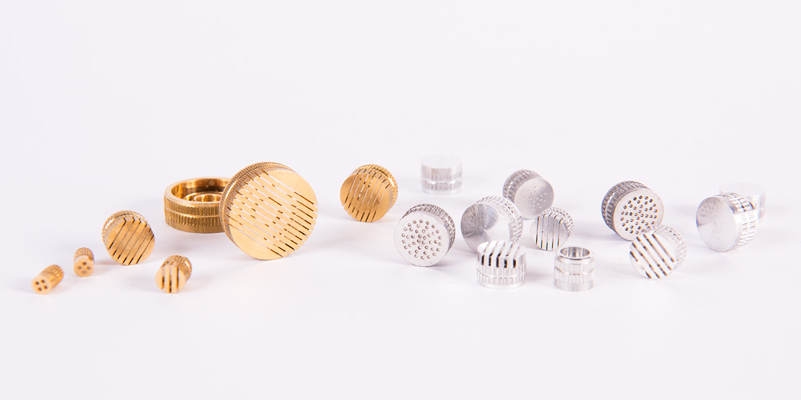 Verschiedene metallene Komponenten wie Injektoren und Entlüftungsdüsen in Gold- und Silberfarbe, hergestellt von Peter Kröner GmbH für die Partikelschaumindustrie.